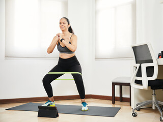 young latin woman doing exercise and at home with rubber bands