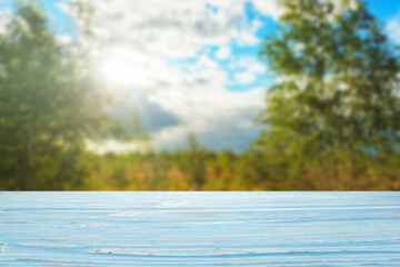 blue wood table top against blurred sky and trees background