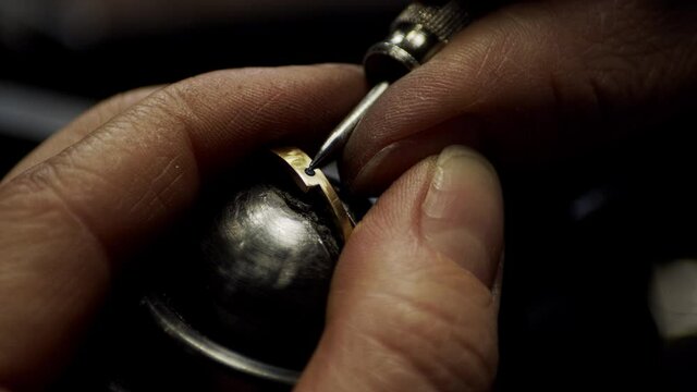Jeweller locking in a small diamond in a freshly made golden engagement ring.