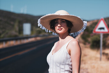 20s age One woman with a straw hat hitchhiking by the country roadside
