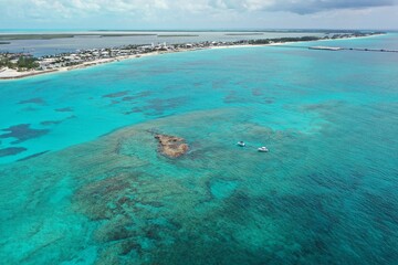 Aerial view of boats anchored near coral rocks with North Bimini coast in background on sunny...