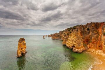 Naklejka premium Amazing beach at sunrise. Algarve in the south of Portugal is a travel vacation destination for many tourists. Beautiful cliffs, caves and crystal clear waters. Europe, Mediterranean sea.