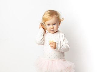 Fototapeta na wymiar funny angry curly caucasian baby girl with a mobile phone in her hands with a serious face on a white background with copy space. concept bad cellular connection.