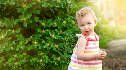 Portrait of little cute caucasian blond baby girl playing outdoors in the grass in the park. happy childhood concept
