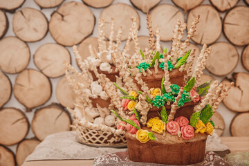 Two pies, decorative multi-tiered pastries with multi-colored cream flowers roses on a wooden background