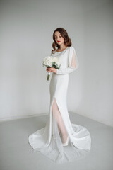 Portrait of a full-length bride in a straight classic white dress with pearls