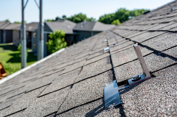 Residential asphalt shingle roof with metal anchors installed for the installation of a solar panel...