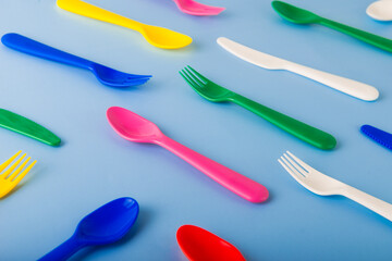 The pattern of reusable cutlery on the blue background. Plastic spoons, forks, knives. Summer...