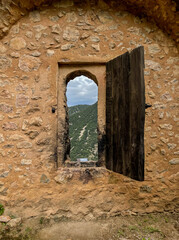 lookout in medieval stone wall and wooden shutter