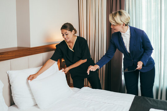 Hotel manager explains to maid how best to tidy up the room.