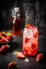 Refreshing summer drink with strawberry and ice in a glass on dark background