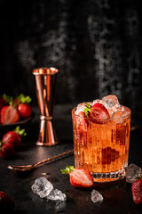 Refreshing summer drink with strawberry and ice in a glass on dark background