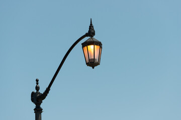 Fototapeta na wymiar street lamp (with bulb illuminated) on a blue sky background