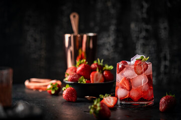 Refreshing summer drink with strawberry and ice in a glass on dark background