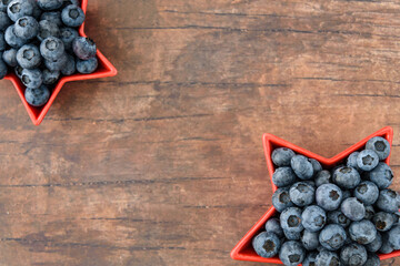 Blueberries for the 4th of July, blueberries in heart shaped bowl, against a wooden background
