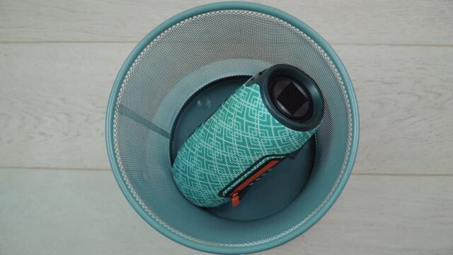 A faulty old portable music player lies at the bottom of a trash can. The trash can spins. Top view. Cell phone repair