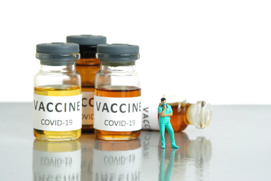 Miniature people toy figure photography. Vaccine alternative choice concept. A nurse standing in front of ampoule bottle.