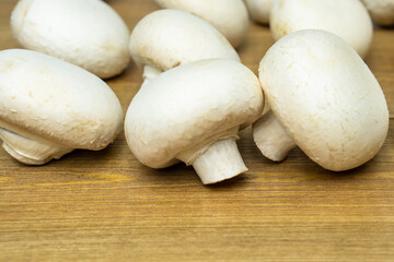 Fresh champignons mushrooms on wooden table, close up.
