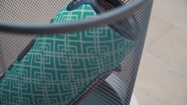 A faulty old portable music player lies at the bottom of a trash can. The trash can spins. Side view through the trash can lattice. Cell phone repair