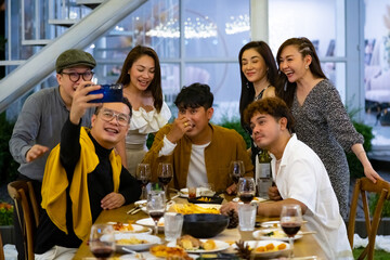 Group of Happy diversity Asian millennial people friends enjoy outdoor dinner party and using smartphone taking selfie together. Reunion friendship meeting celebration party and night life concept.