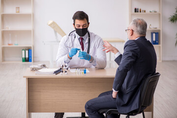 Old businessman visiting young male doctor in vaccination concep
