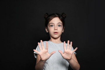 Little girl feeling fear on black background