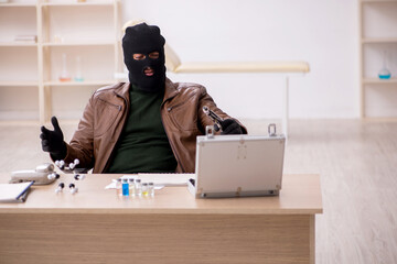 Young man in balaclava stealing vaccine from the lab