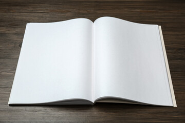 Open blank paper brochure on wooden table. Mockup for design
