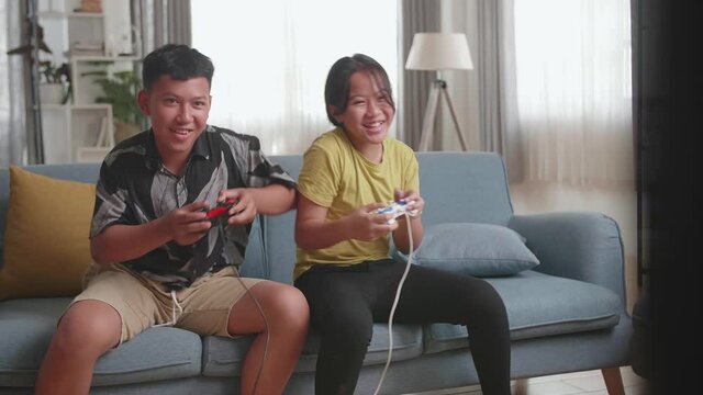 Funny Asian Children With Joystick Game Playing Video Games On Tv At Home
