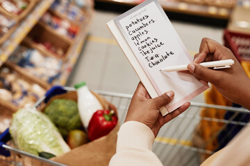 Close up of unrecognizable African-American woman holding shopping list while buying food in...