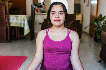 hispanic girl with Down syndrome improving her flexibility by stretching on yoga mat at home disability concept in Latin America	
