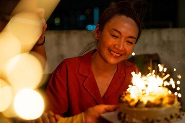 Diversity Asian millennial people friends enjoy celebration birthday party together at outdoor rooftop with food and drink. Woman excited with birthday cake and blowing birthday candle with happiness - Powered by Adobe