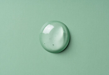 Transparent gel drop on green background. Liquid gel texture. Beauty serum drop.