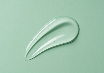Transparent gel drop on green background. Liquid gel cosmetic stain texture. Beauty serum drop.