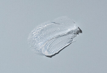 Transparent cosmetic cream on gray background.