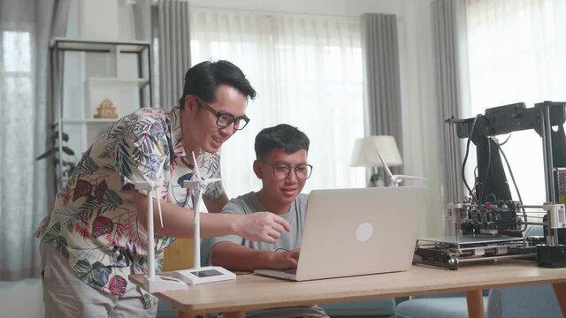 Father Teach His Son Using Laptop Computer Programming Electric Wind Turbine Model And 3D Printer At Home
