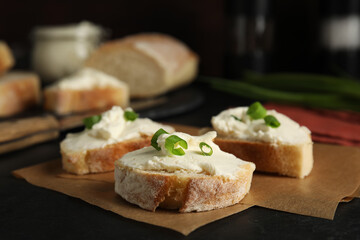 Fototapeta na wymiar Bread with cream cheese and green onion on black table