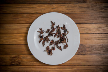 Dry Star Anise on white plate, wood background, ingredient seasoning herb vegetable