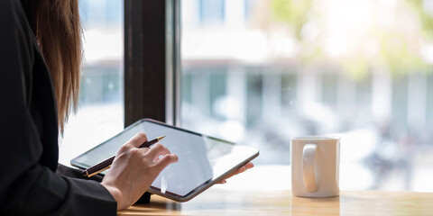 Above view of woman holding digital tablet and stylus pen on her office desk.