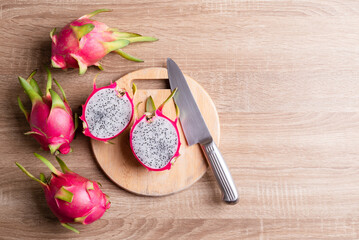 Dragon fruit or pitaya on cutting wooden board with kitchen knife on wooden background, Tropical fruit, Table top view