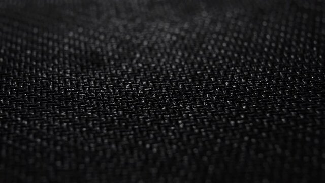 Black synthetic fabric texture. Background pattern. Macro. Dolly shot