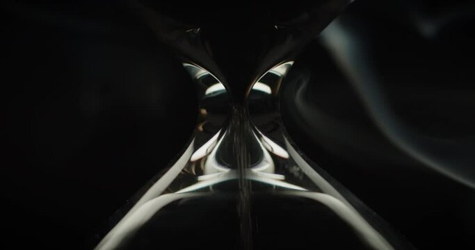 Close up of sand pouring in hourglass on the black background and smoke rising slowly. 