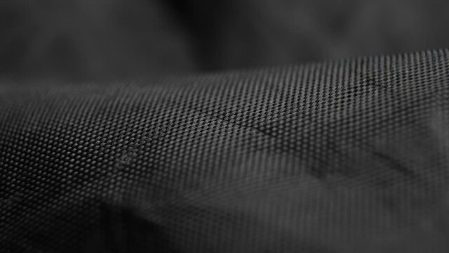 Wavy black synthetic fabric. Macro. Dolly shot. Texture crease