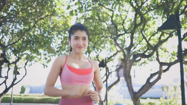 Sporty Asian female athlete in sportswear running in morning park for a healthy and fit body. Young woman jogging outdoors