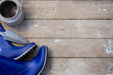 Rubber boots, scoop and tools on background of old boards. Flatlay