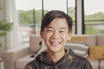 POV Portrait of happy Asian preteen teen boy smiling and making video calling at home, using zoom...