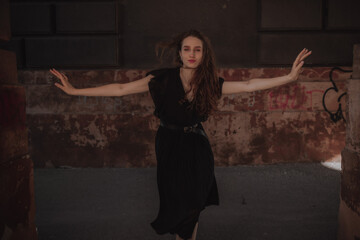 Curly girl in a black dress against the backdrop of the city