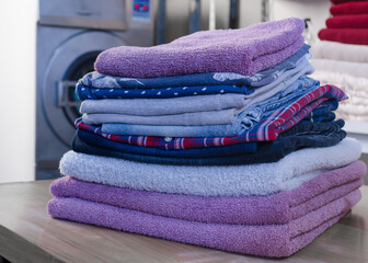 Stack of folded pastel colors clothes in a laundry. Clean and soft clothes pile.