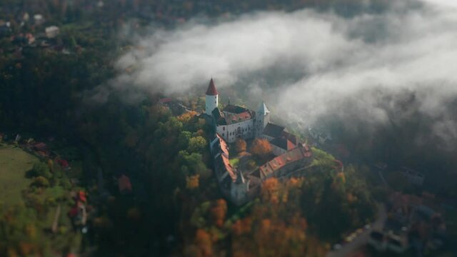 An aerial view of the beautiful Krivoklat (Křivokl&aacute;t) Castle in Central Bohemia. The gothic castle standing on the forest-covered hill, the thin haze floating above it. Villages surround the castle.