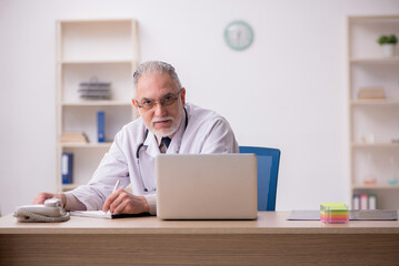Obraz premium Old male doctor working in the clinic